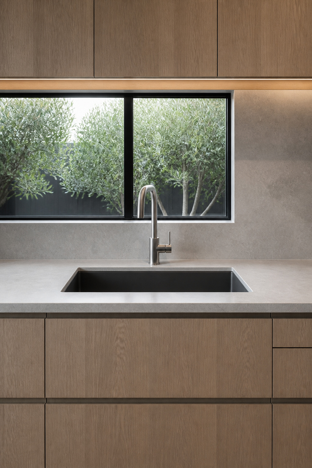 An undermount composite sink sitting flush with a honed quartzite countertop, paired with a slender arc tap and no accessories — the minimalistic kitchen sink zone at its most resolved.