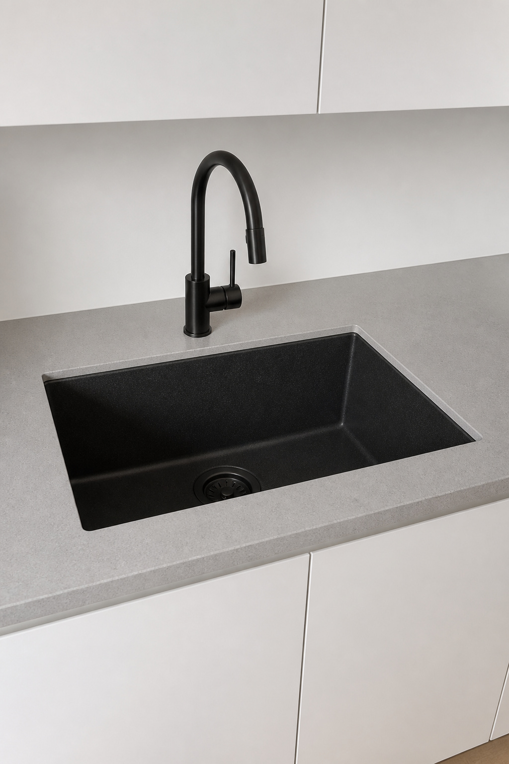 A matte black composite undermount sink with no visible rim lets the quartz countertop read as a single unbroken plane.