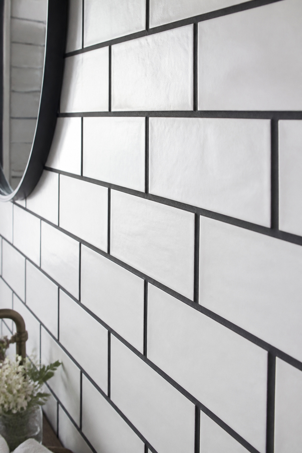 Dark grout transforms standard white subway tile from a background material into a deliberate graphic statement in any apartment bathroom.