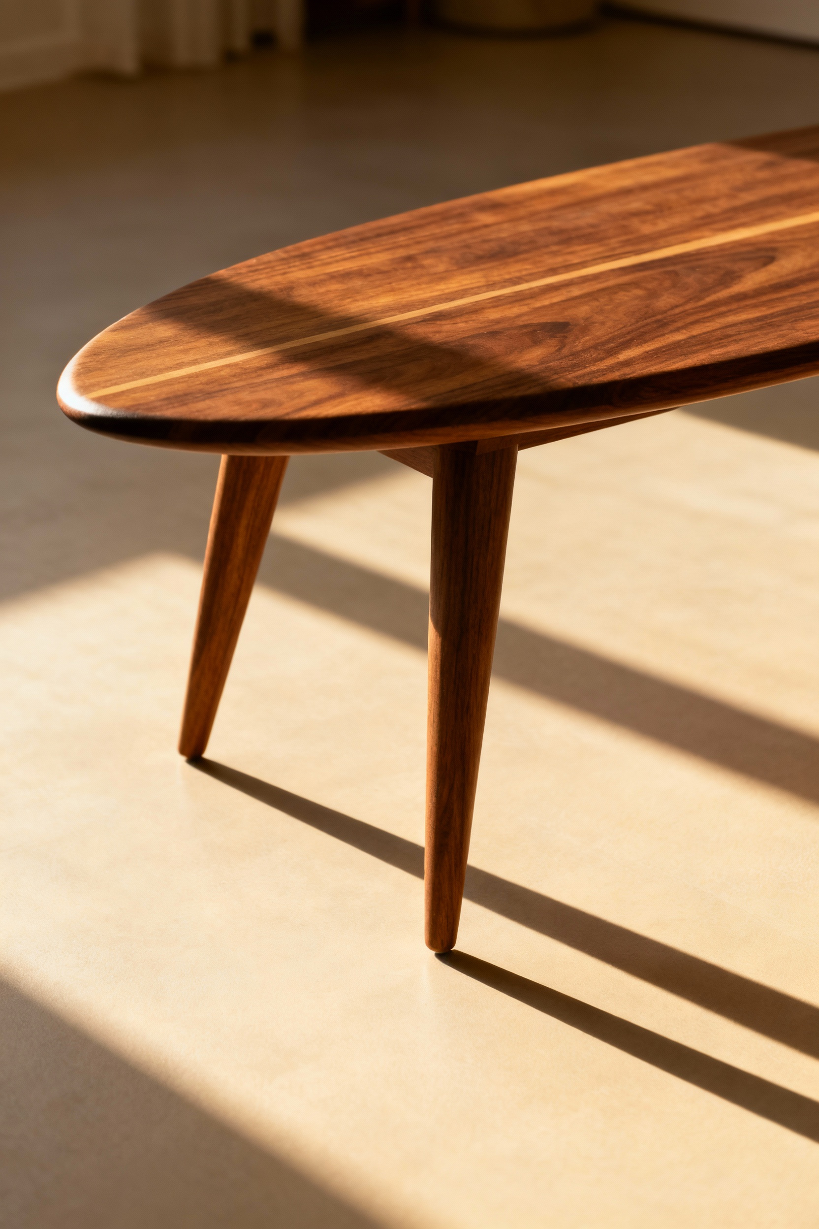 A low-angle shot of a Mid-Century Modern walnut surfboard coffee table featuring tapered, splayed legs that create a floating effect, emphasizing negative space and lightness.