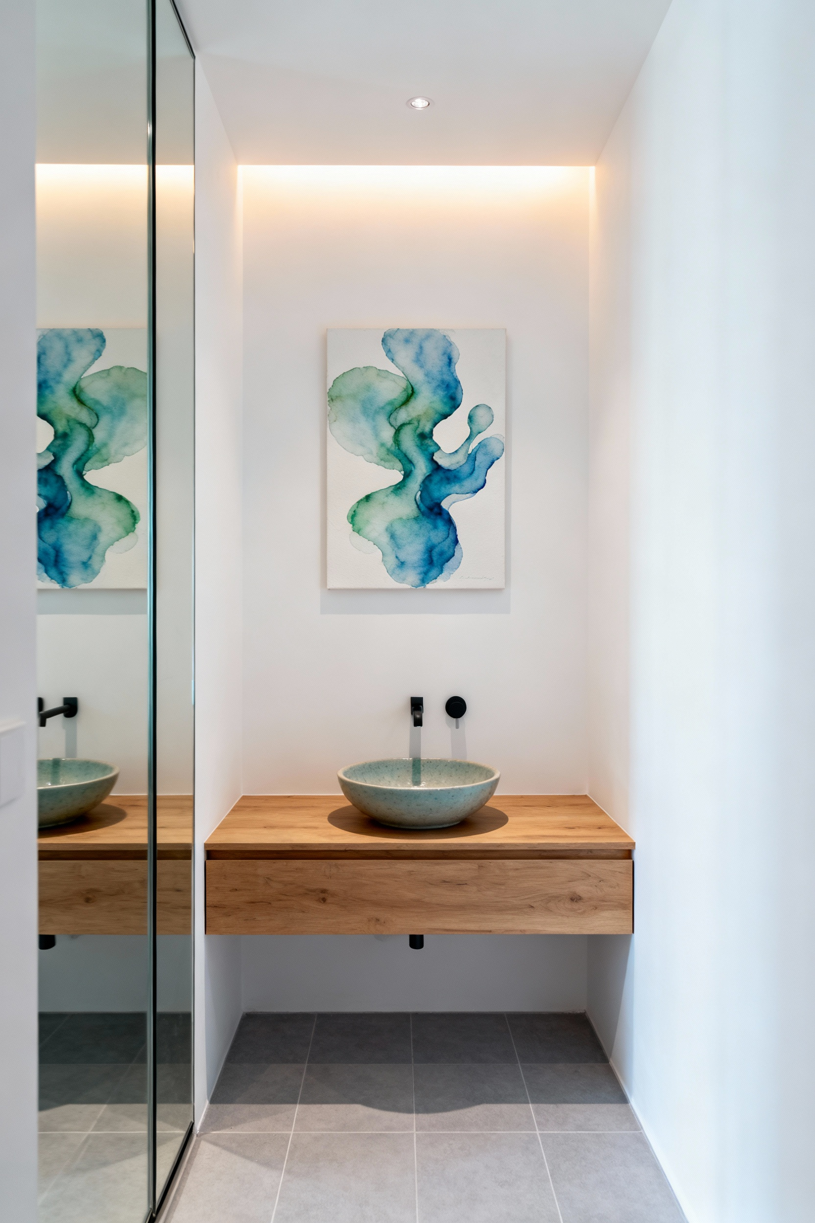 Elegant small bathroom interior featuring a large abstract watercolor painting in blues and greens above a floating vanity, serving as a tranquil focal point, illuminated by a subtle accent light, enhancing visual serenity.
