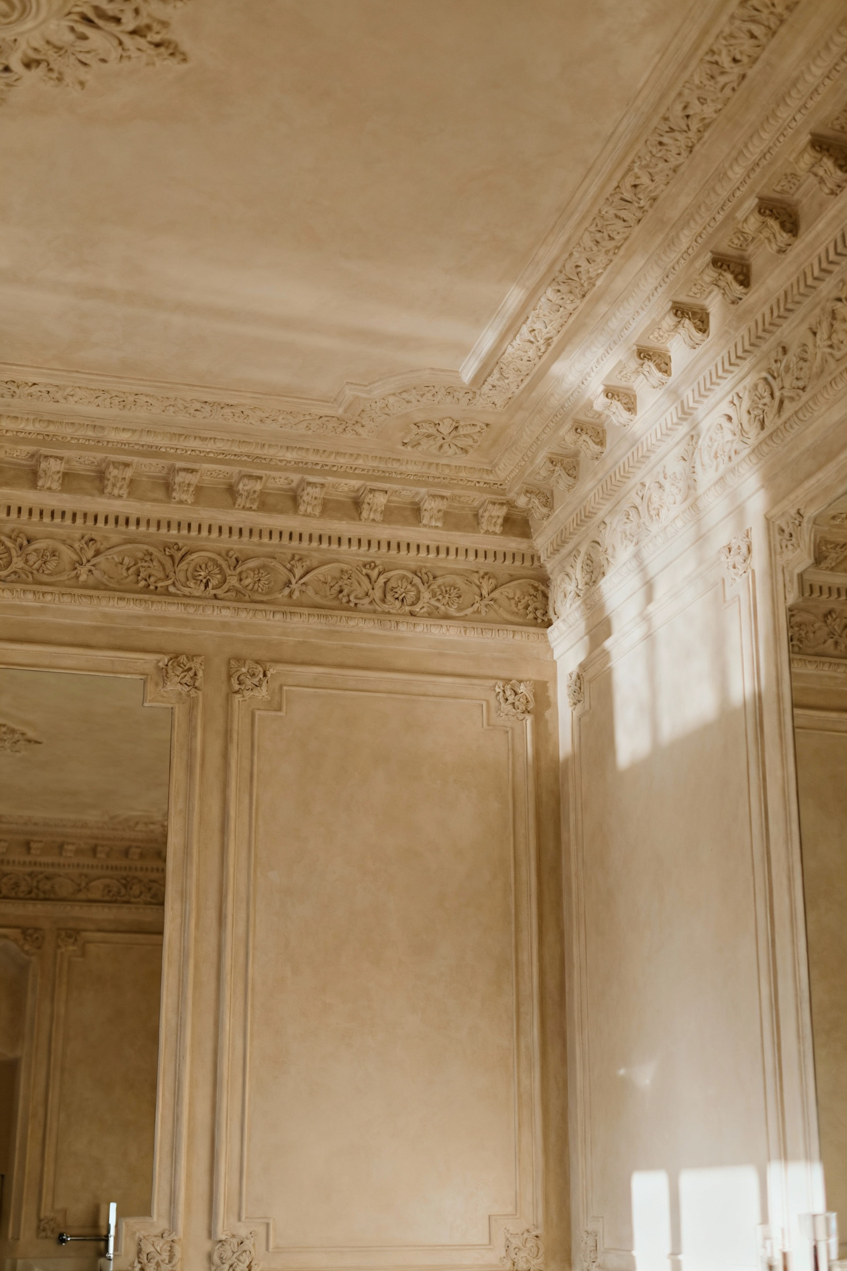 A luxurious traditional bathroom interior displaying intricate friezes, elegant cornices, and detailed plasterwork accents on the upper walls and ceiling, bathed in soft natural light.