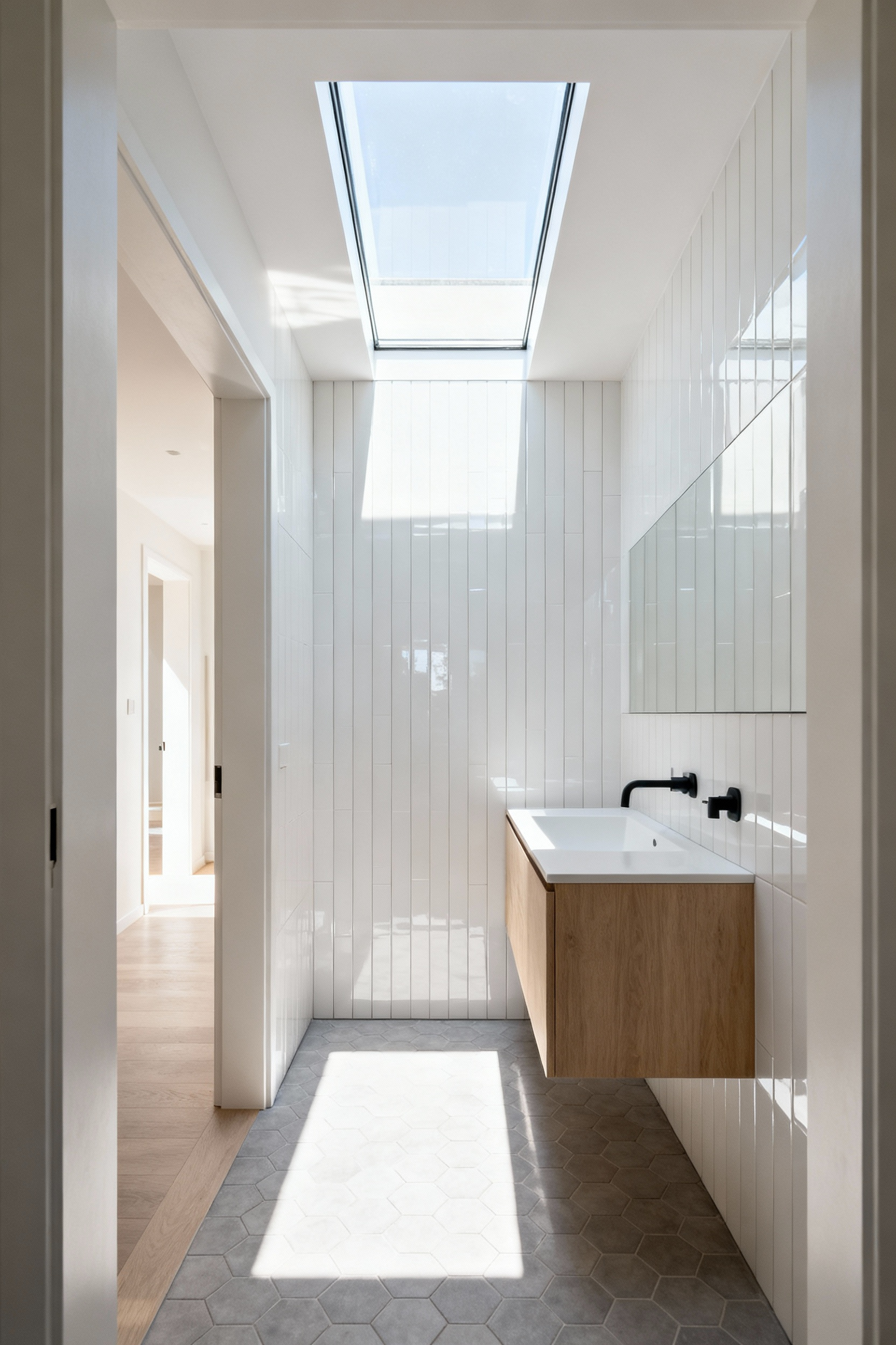 Small modern bathroom layout utilizing a clear glass transom window above the doorway to allow borrowed light from the adjacent hallway, creating an illusion of expanded vertical space.