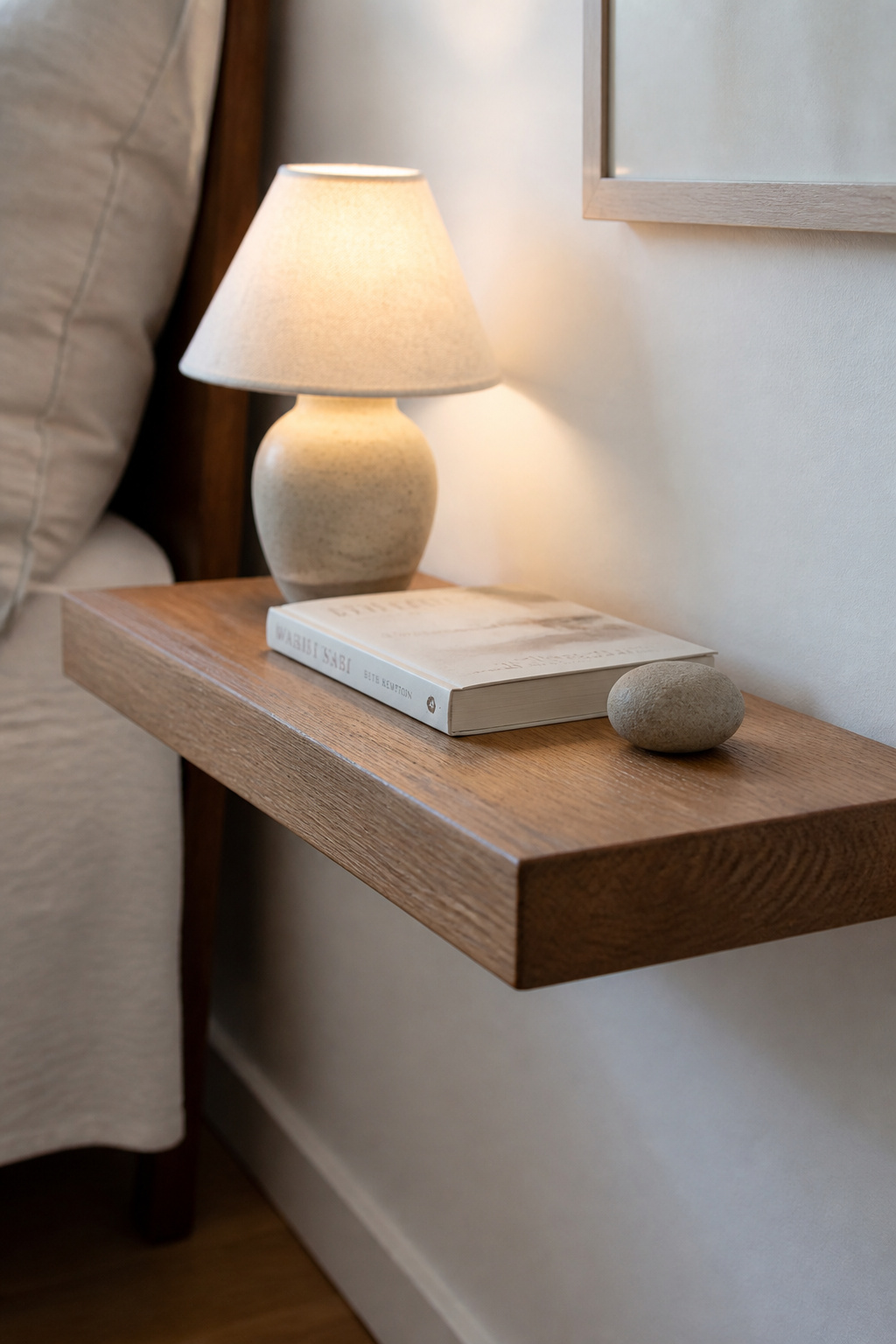 A floating shelf forces a discipline that a conventional nightstand cannot — its limited surface area keeps the bedside environment genuinely minimal.