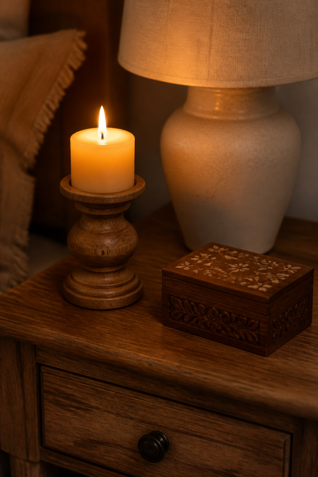 A turned wood candle holder and carved trinket box on the nightstand tie the room's natural material language together at the small-scale detail level.