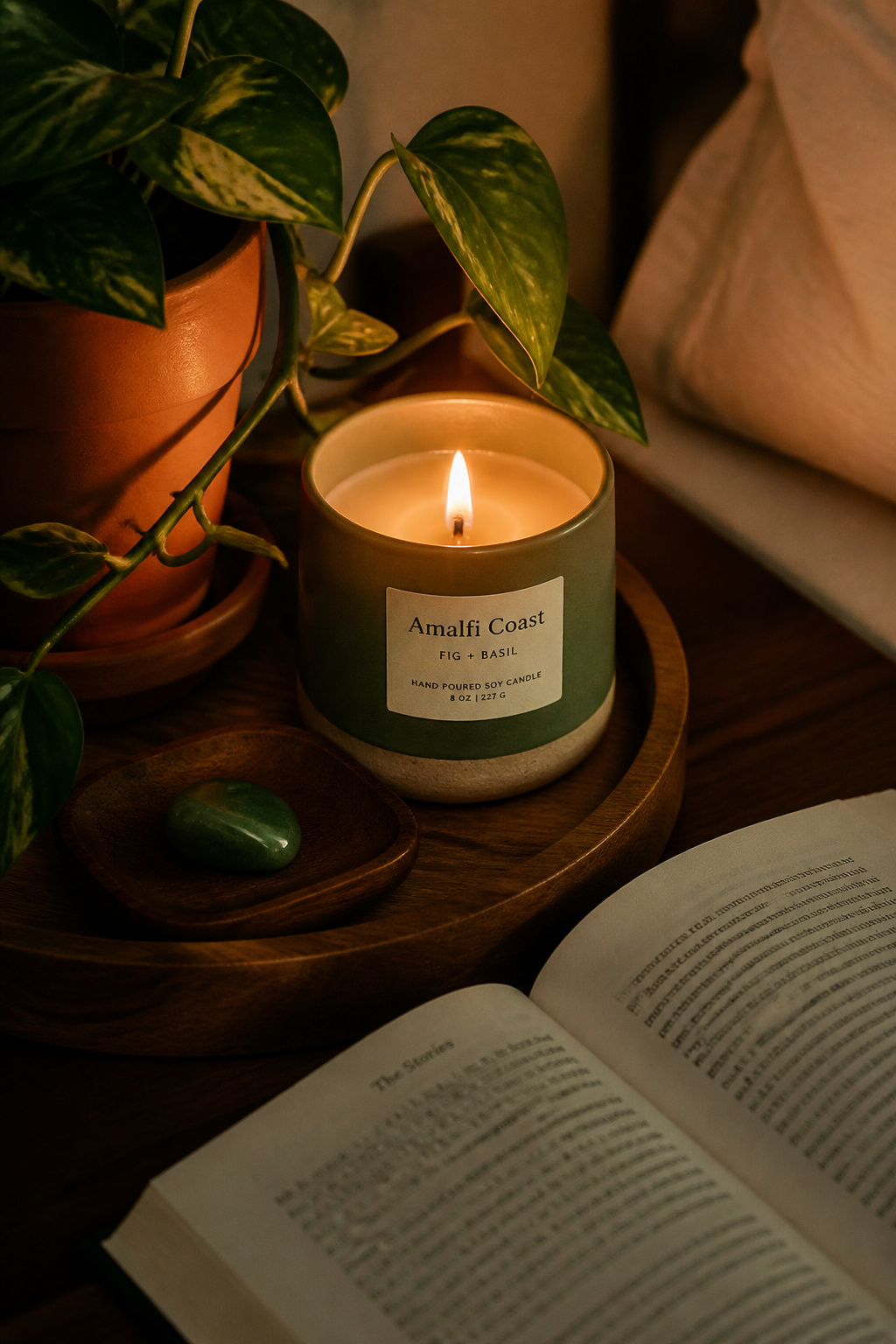 A bedside wellness arrangement — green candle, jade crystal, trailing plant — creates a deliberate sensory anchor that supports the sleep transition ritual.