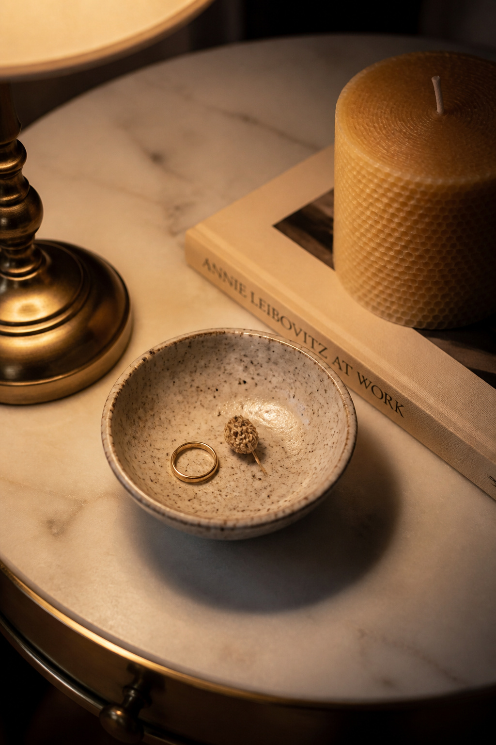 A hand-thrown stoneware dish holds a ring and a dried seed — functional objects that become decor when placed in a vessel with genuine character.