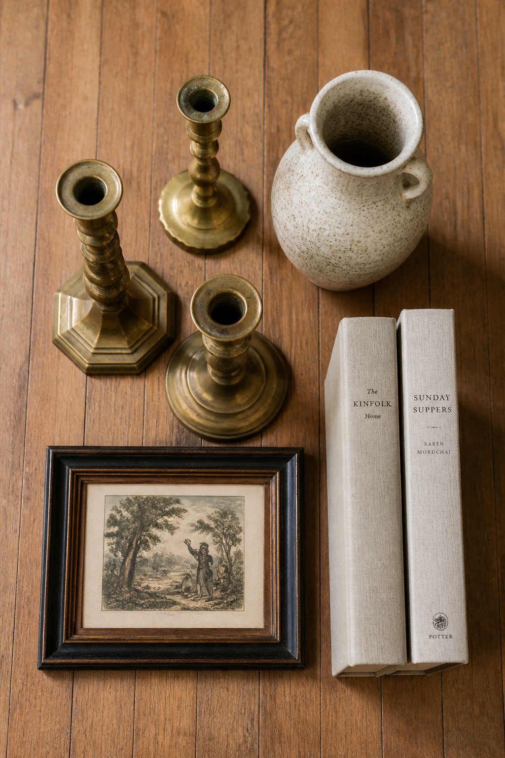 A full end table decor set sourced from thrift stores: brass candlesticks, ceramic vase, hardback books, and a framed print — total cost under $20.