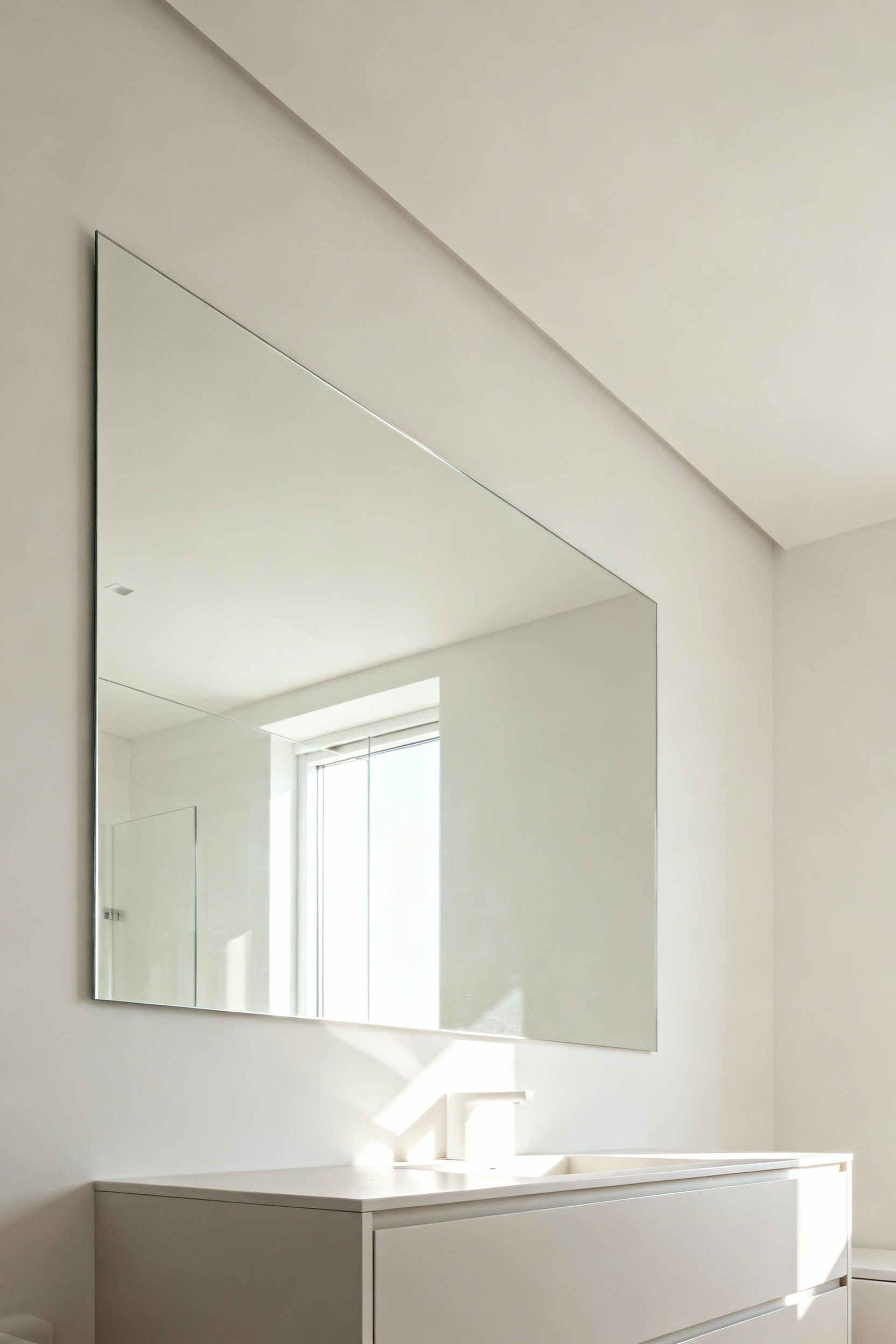 Modern bathroom with a large frameless mirror reflecting natural light, visually expanding the spacious and bright interior.