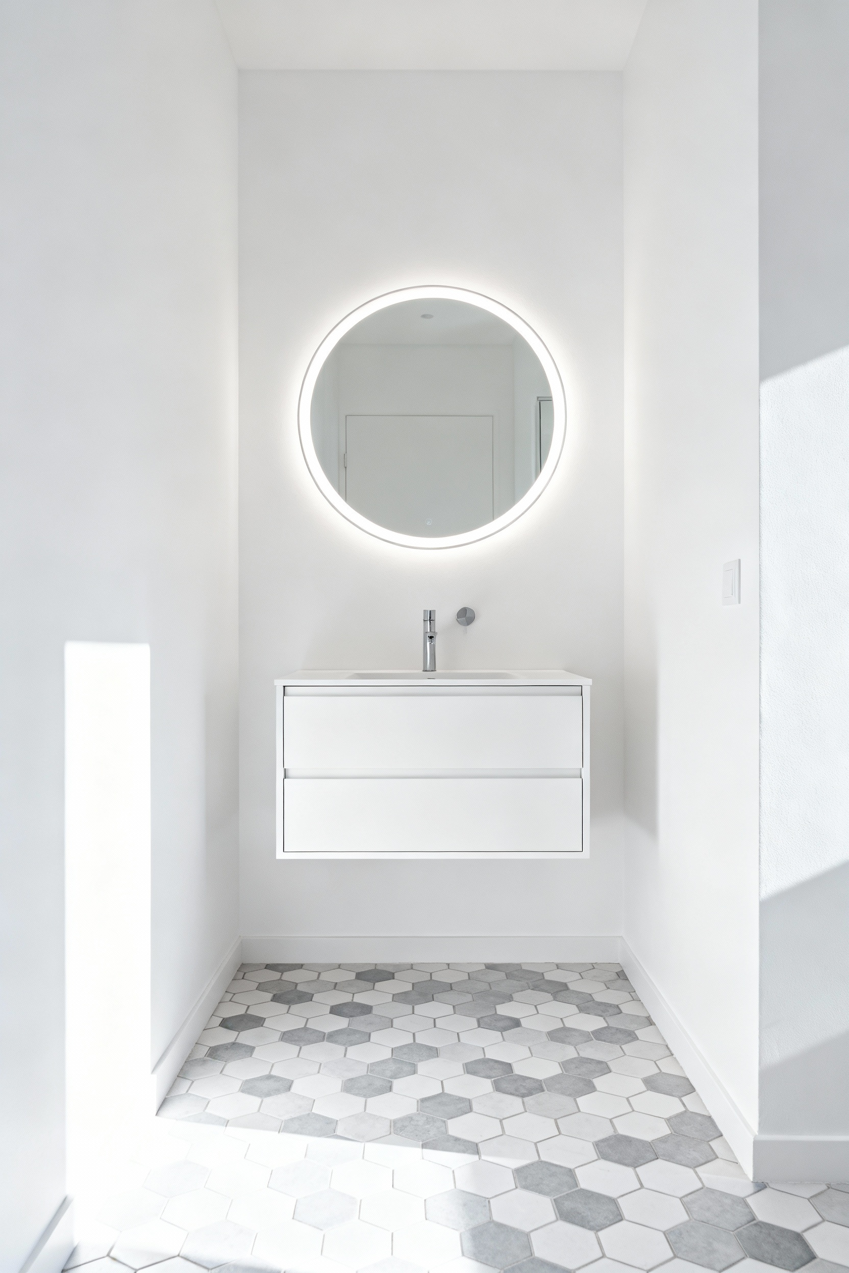 A modern small bathroom featuring a floating white wall-mounted vanity which exposes the continuous geometric floor tile underneath, demonstrating how reclaiming floor space makes the room feel significantly larger and airy.