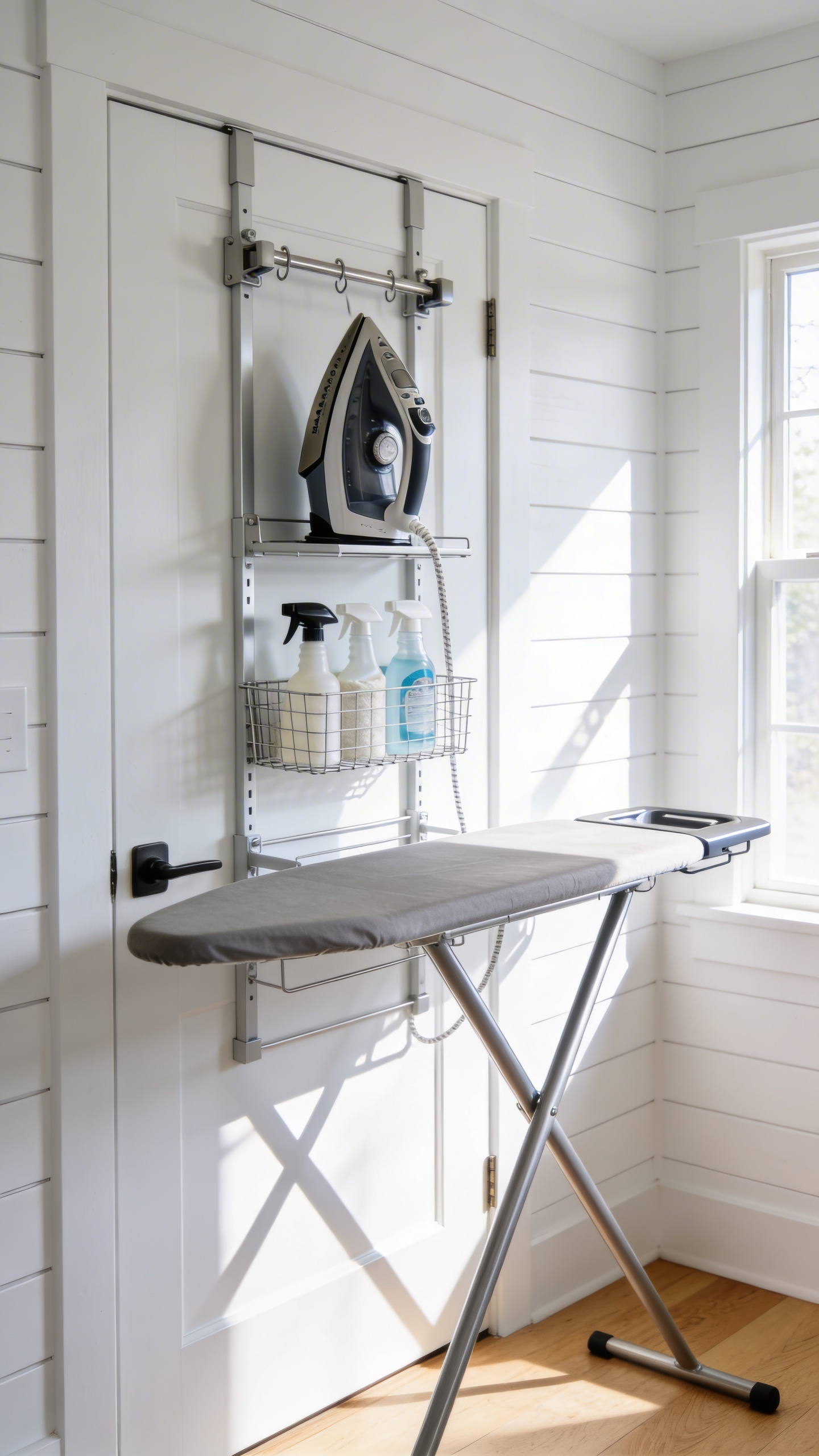 A well-organized laundry room with an over-the-door rack on a white door holding a steam iron and ironing board.