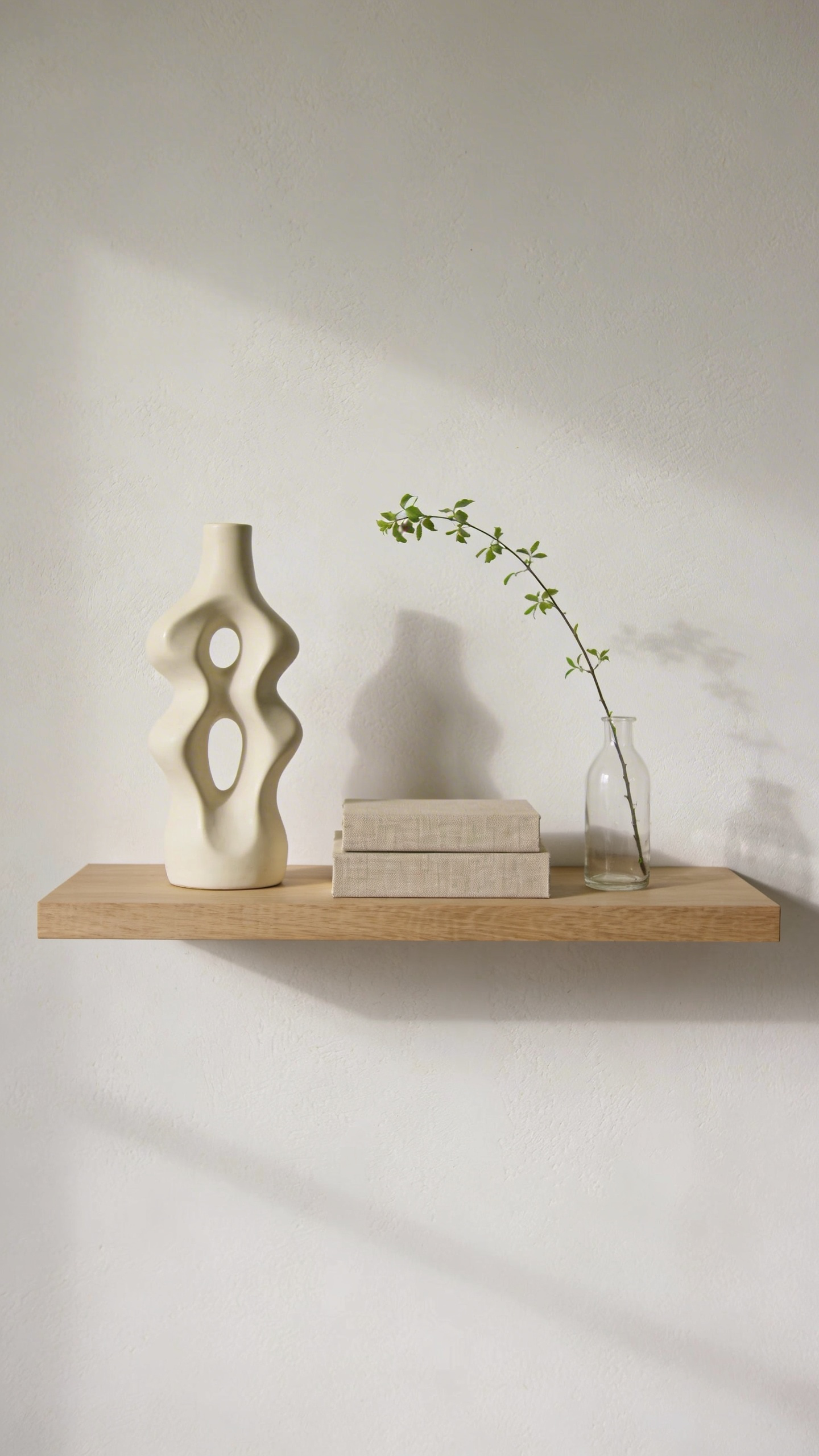 A highly minimalist living room shelf with three carefully curated decorative items, illustrating the decluttering principle of mindful acquisition and maintenance.