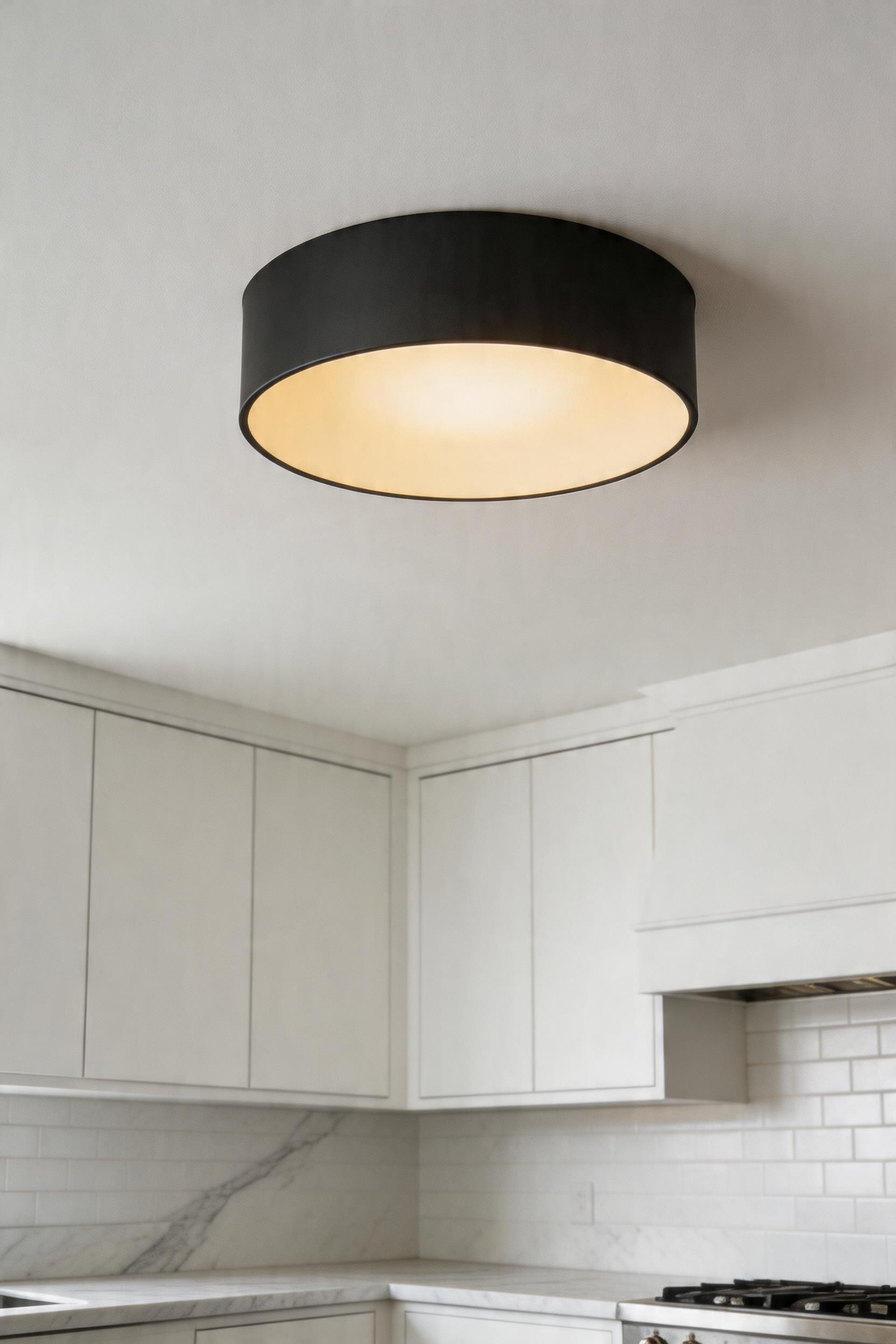 A flush-mount drum shade ceiling light providing clean ambient coverage in a low-clearance kitchen.