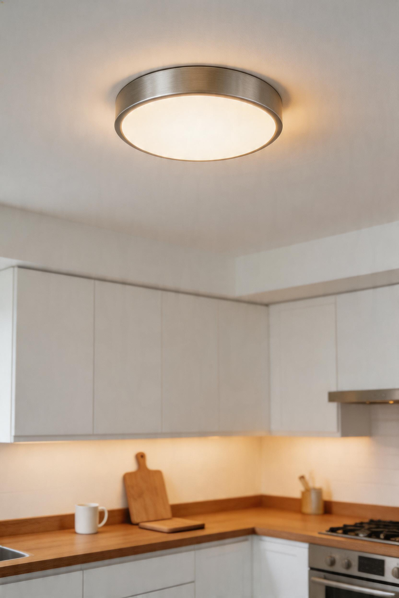 A tunable LED flush-mount ceiling light adjusting colour temperature from warm 2700K to cool 4000K for different kitchen activities.