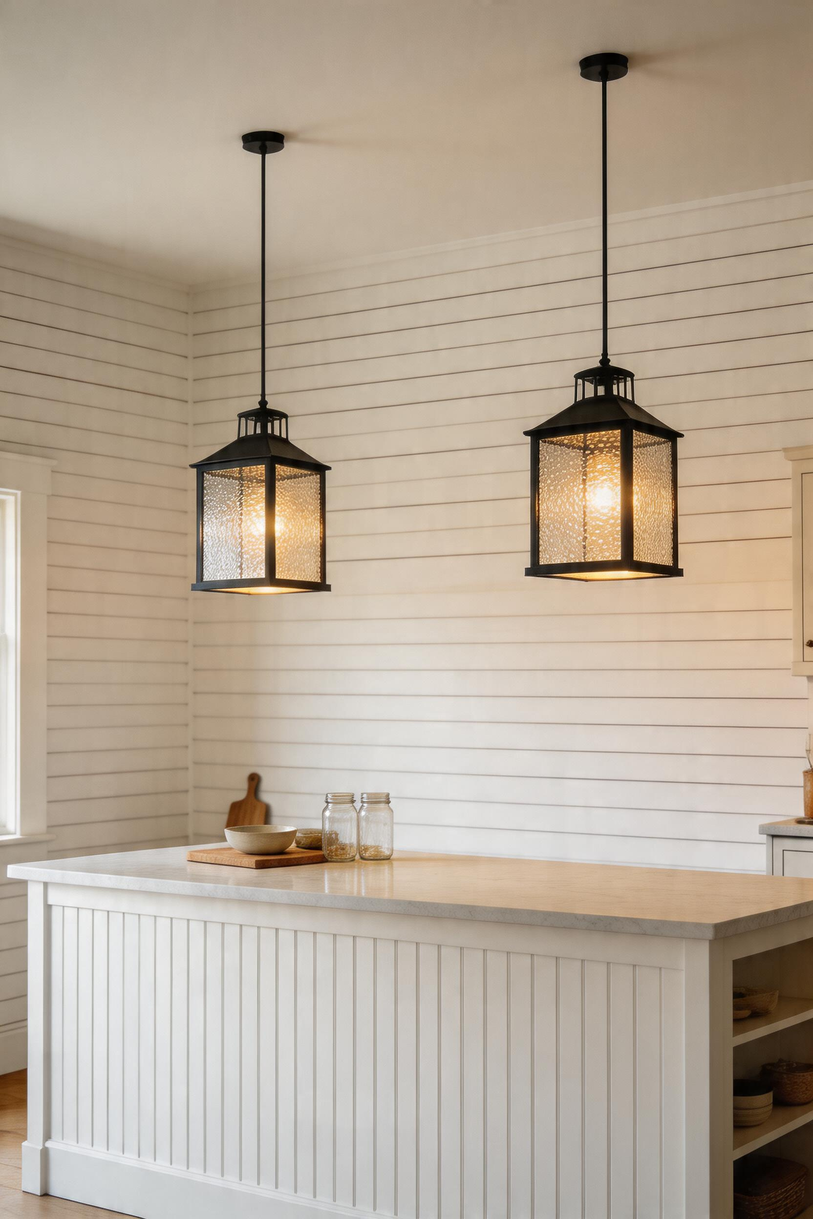 Two seeded glass lantern pendants providing soft, diffused light over a farmhouse kitchen island.