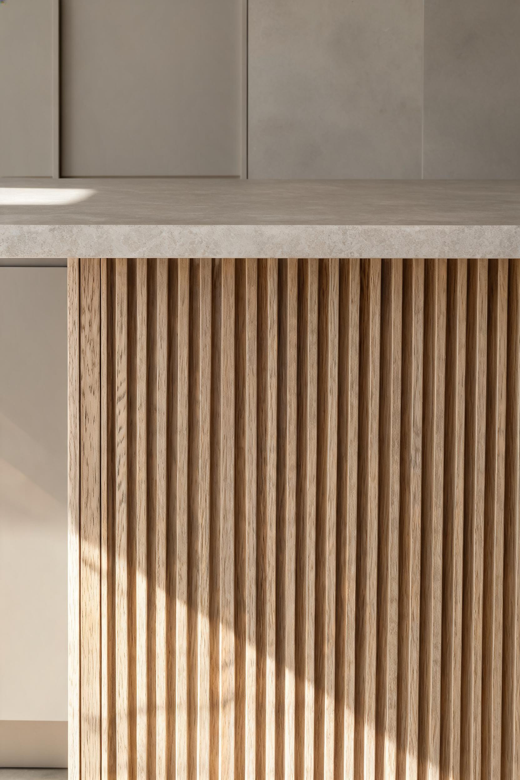 Fluted white oak channels on the island face cast shifting shadow lines under natural light -- one bold material doing the visual work that pattern and decoration would do in any other kitchen style.