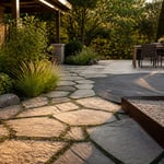 A layered outdoor patio showcasing multiple natural stone surfaces — flagstone with creeping thyme joints, composite decking, and travertine — demonstrating how material zoning transforms an outdoor space.