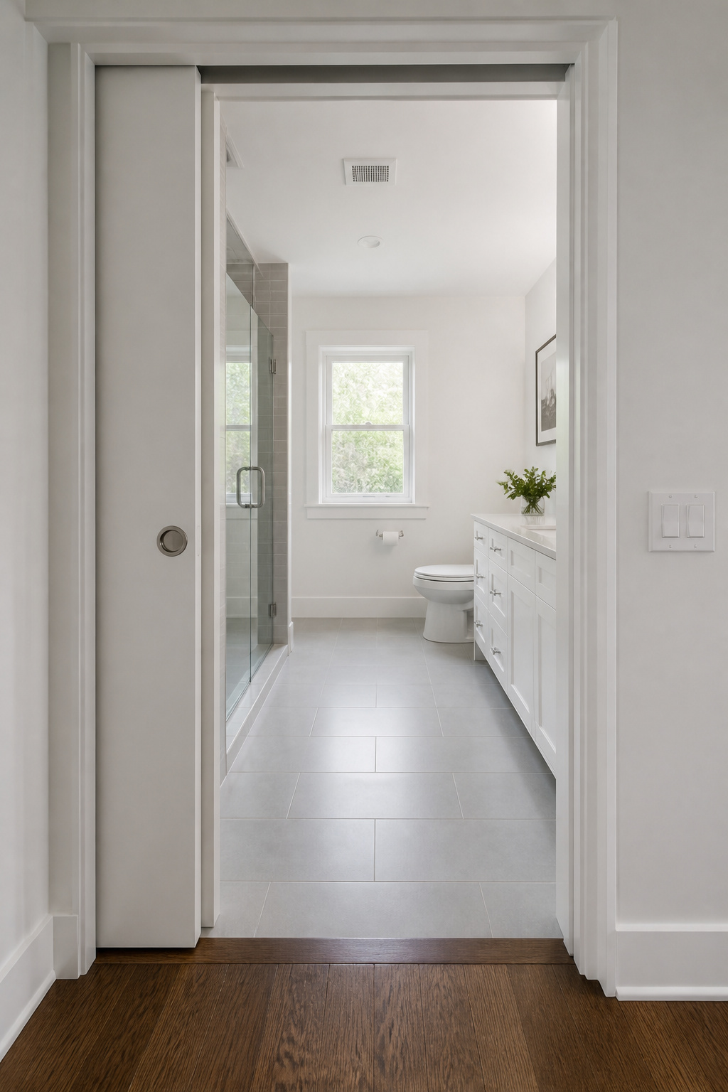 A fully recessed pocket door shows just how much floor space a swing door was claiming — the bathroom floor runs clear from wall to wall once the arc is eliminated.
