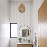 Floor-to-ceiling 4x12 elongated subway tile installed vertically with gray grout creates a strong upward visual movement that makes this small bathroom's 8-foot ceiling feel considerably taller.