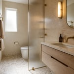 A small bathroom that combines travertine, aged brass, white oak, and terrazzo demonstrates that the size of the canvas does not limit the ambition of the material conversation.