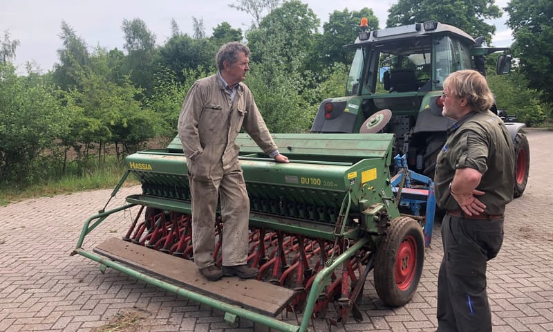 Boswachter en boer op zaaimachine