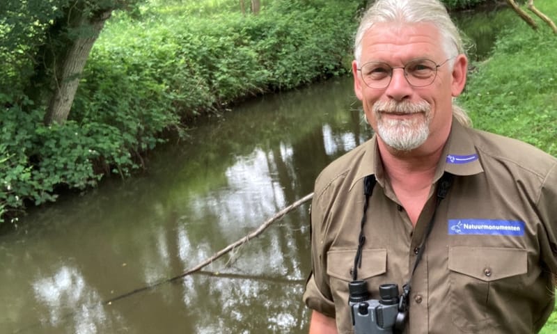 Peter Voorn met verrekijker aan de beek