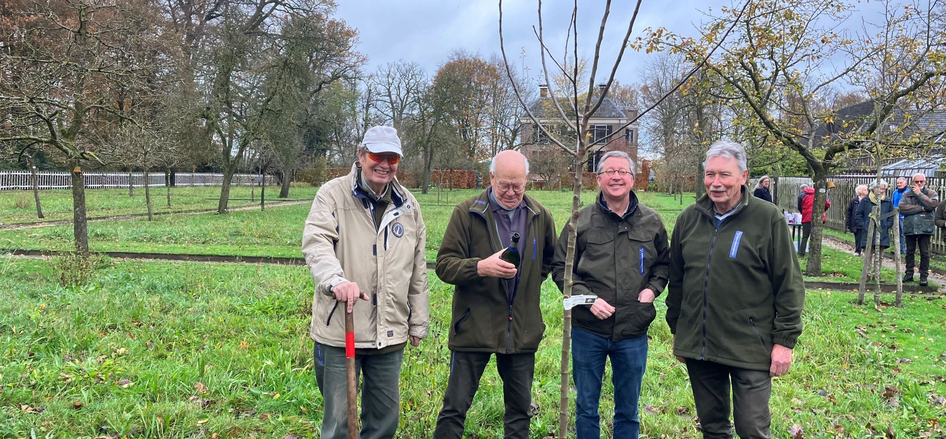 drie vrijwilligers (80 jaar) planten boom op Velhorst