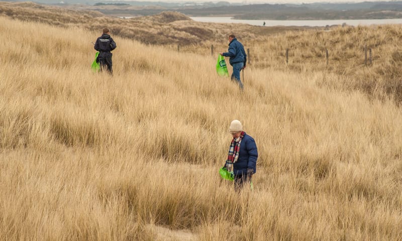 Vrijwilligers ruimen zwerfafval op in de duinen van het Zwanenwater