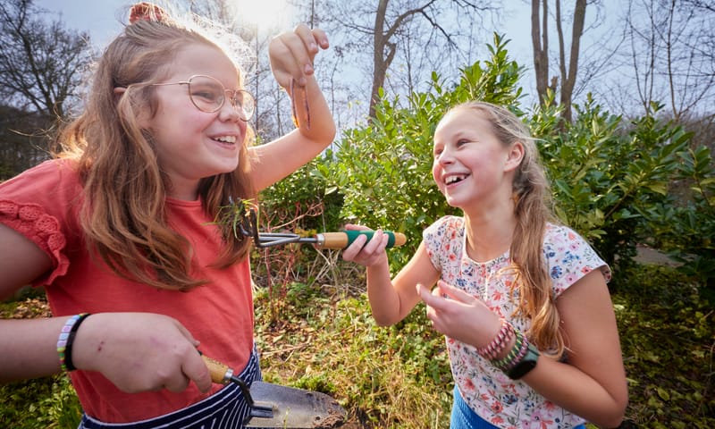 Twee meisjes vinden een regenworm in de natuur