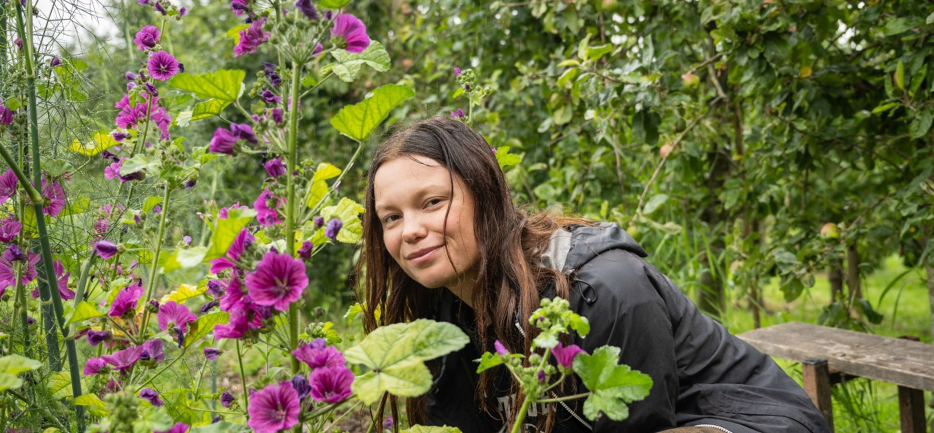 Dame (Ida Simonsen) die tussen de bloemen door naar de camera kijkt