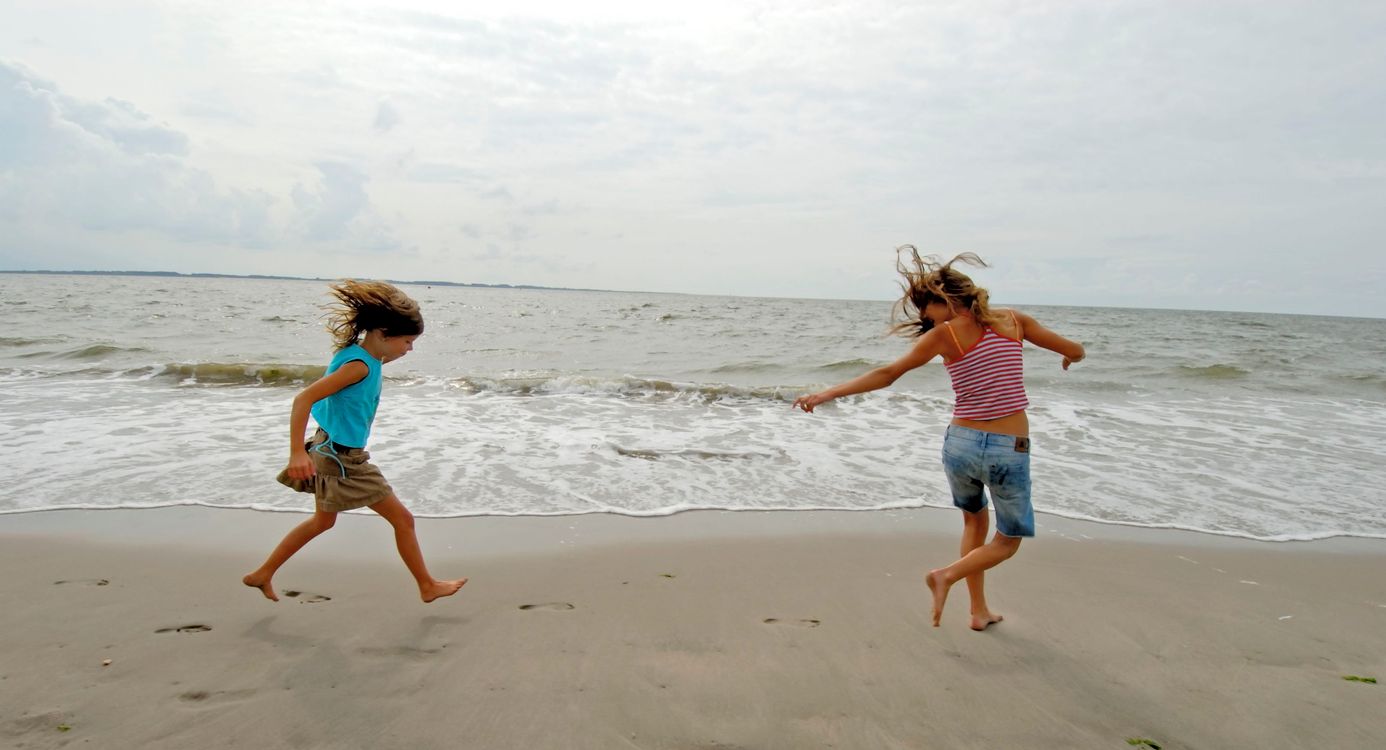 Twee kinderen die op de rand van strand en zee aan het spelen zijn