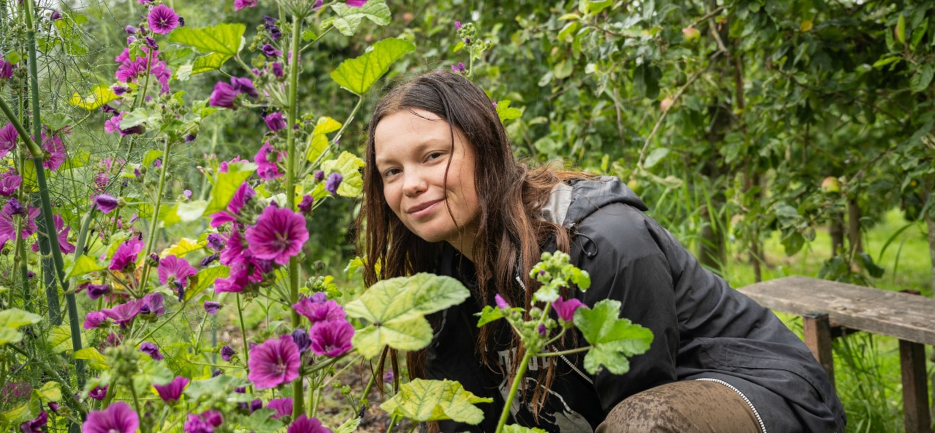 Dame (Ida Simonsen) die tussen de bloemen door naar de camera kijkt