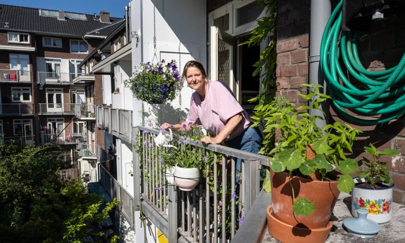 Dame die op een balkon vol planten staat