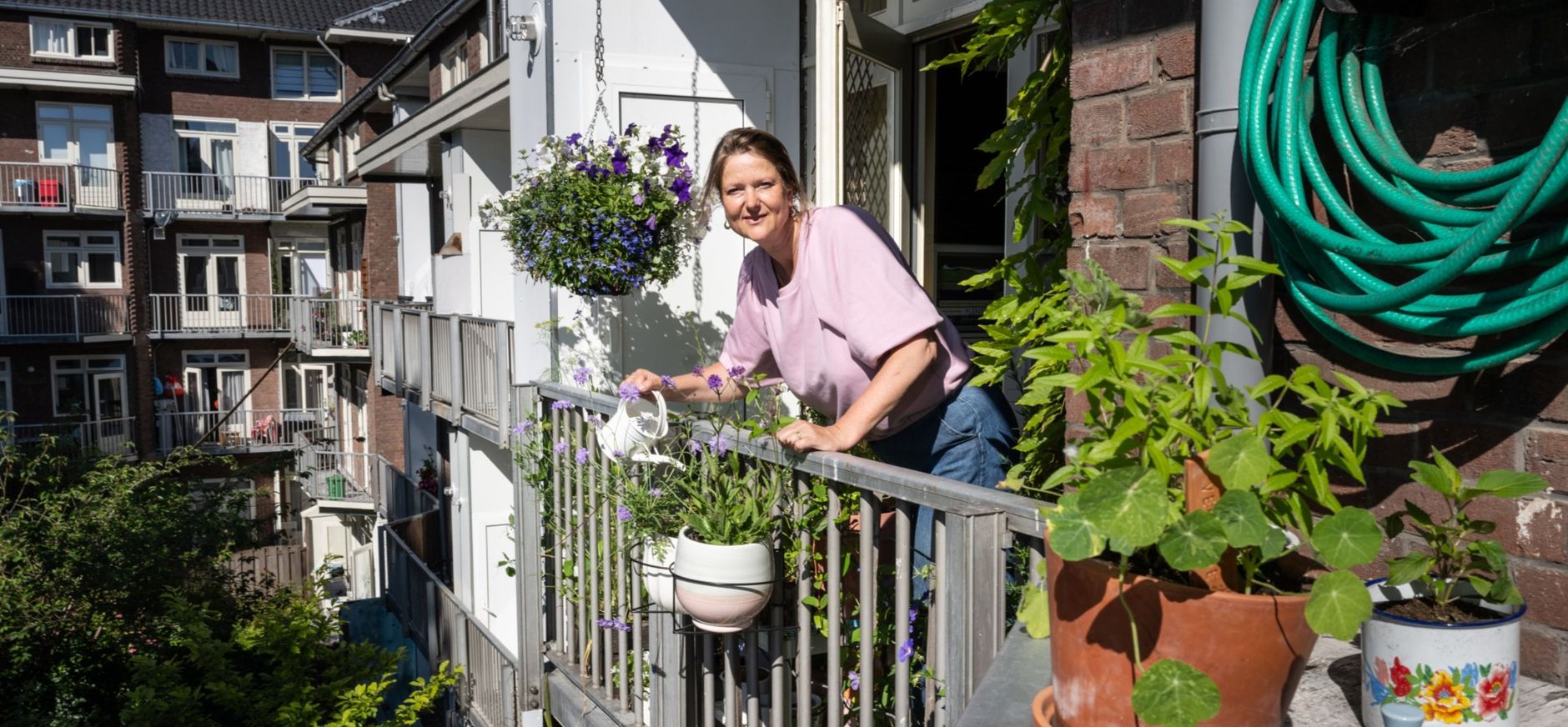 Dame die op een balkon vol planten staat