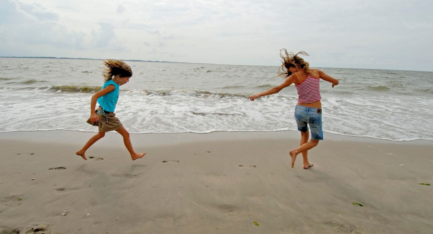 Twee kinderen die op de rand van strand en zee aan het spelen zijn