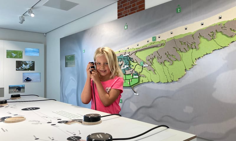 meisje dat luistert via een luisterschelp in de expositie van informatiecentrum Het Baken