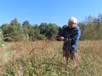 Jacques Rovers van Floron in het veld met een wilde plant
