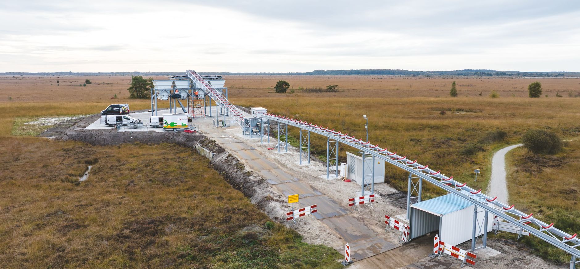Elektrische transportband voor zand en leem bovenover fietspad de Bonghaar