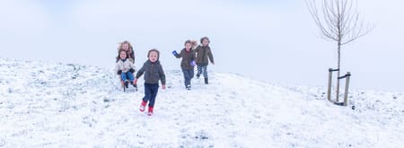 Kinderen rennen van een besneeuwde heuvel naar beneden