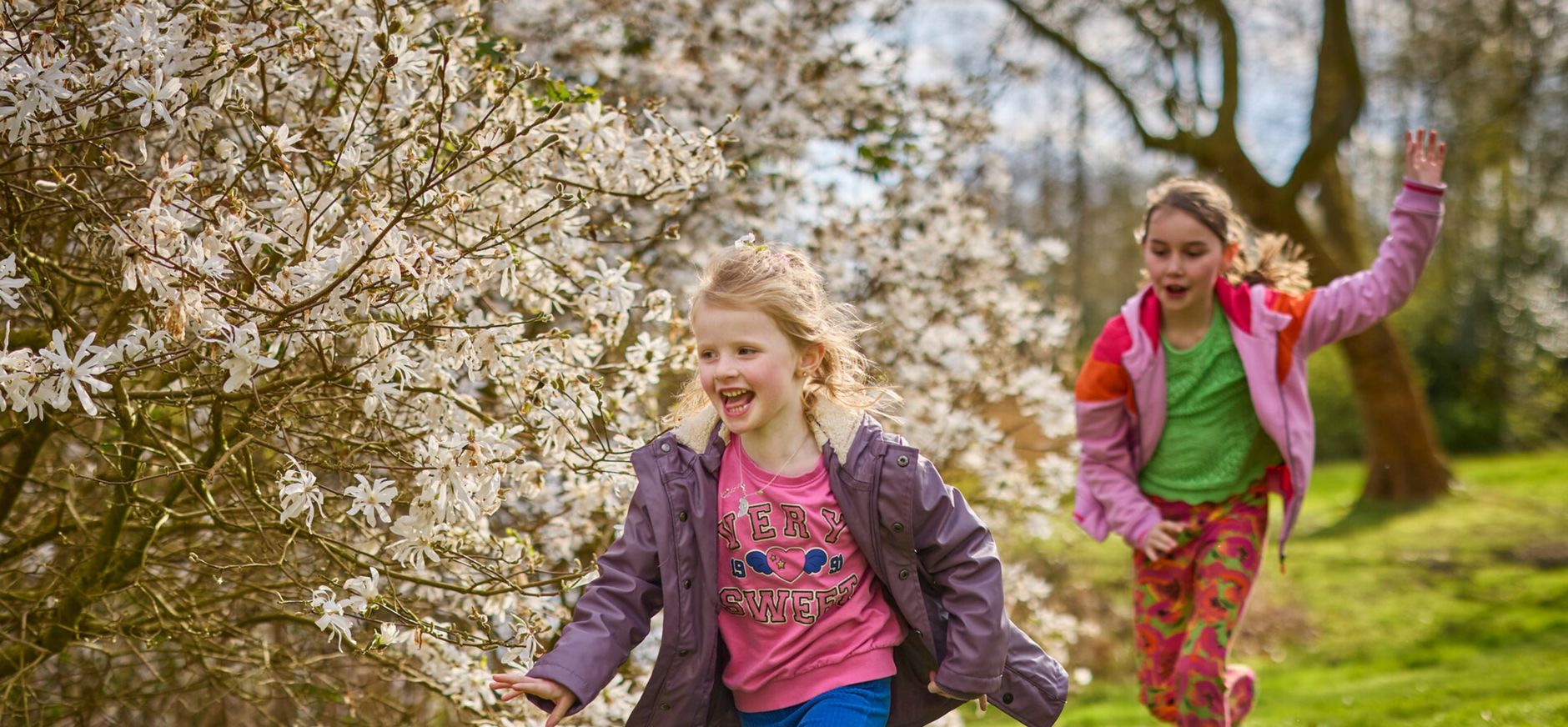 Twee kinderen aan het rennen, langs een bloeiende meidoorn