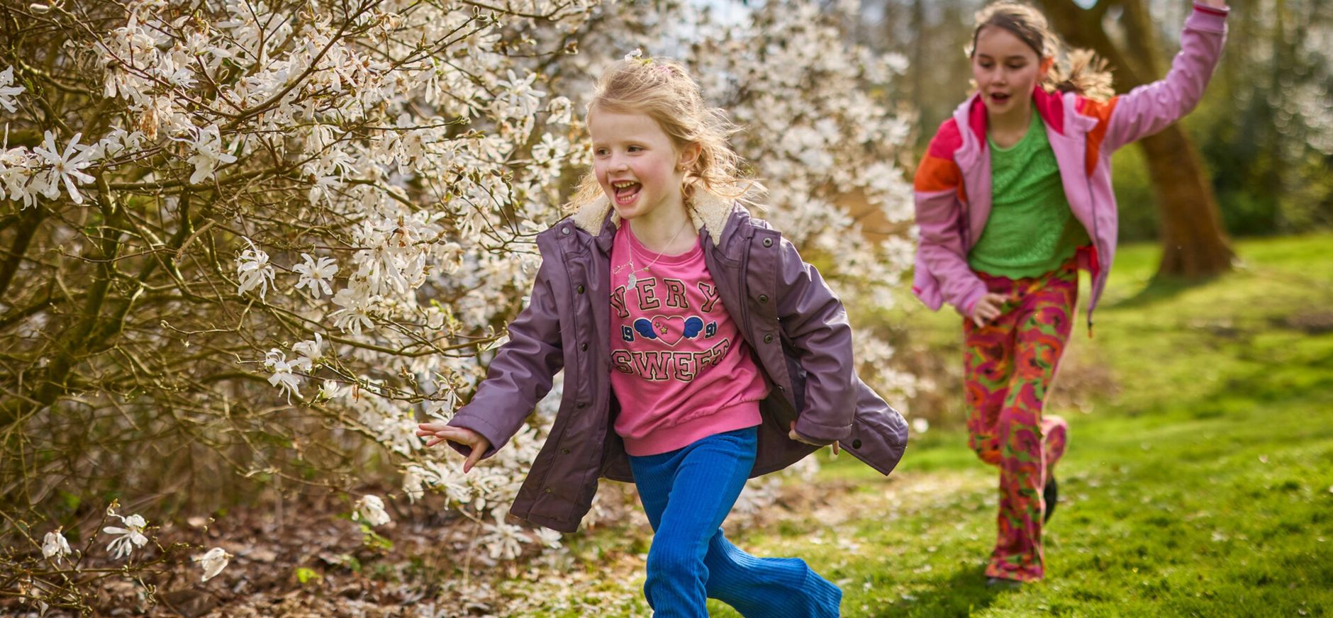 Twee kinderen aan het rennen, langs een bloeiende meidoorn