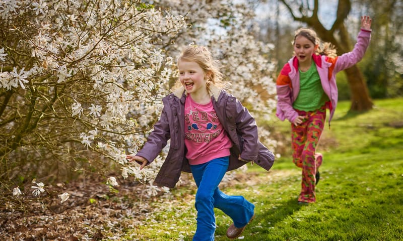 Twee kinderen aan het rennen, langs een bloeiende meidoorn