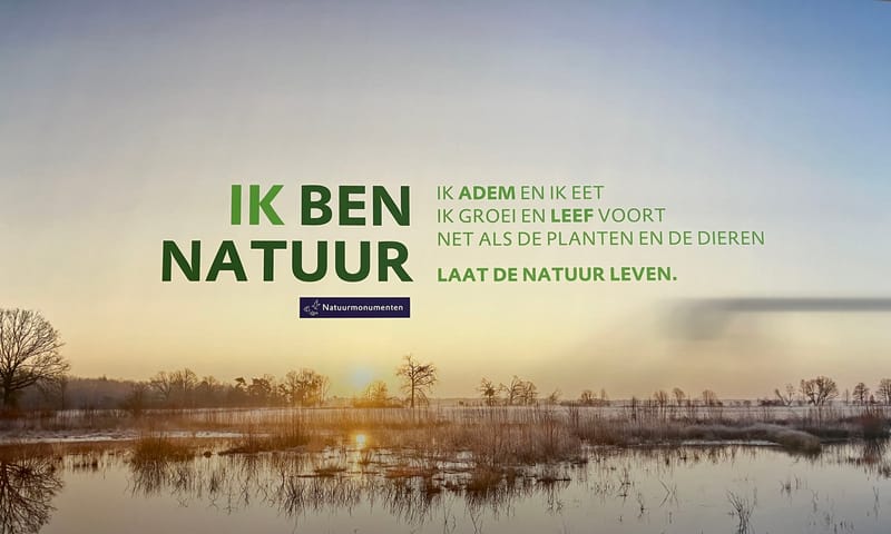 De foto op de wand achter de balie met de tekst IK BEN NATUUR