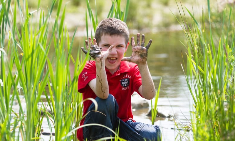 Kind met vieze handen van de modder voor zijn gezicht