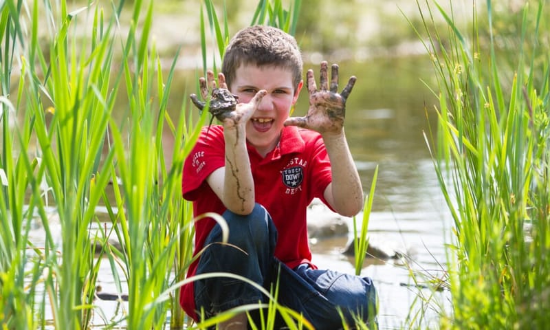 Kind met vieze handen van de modder voor zijn gezicht