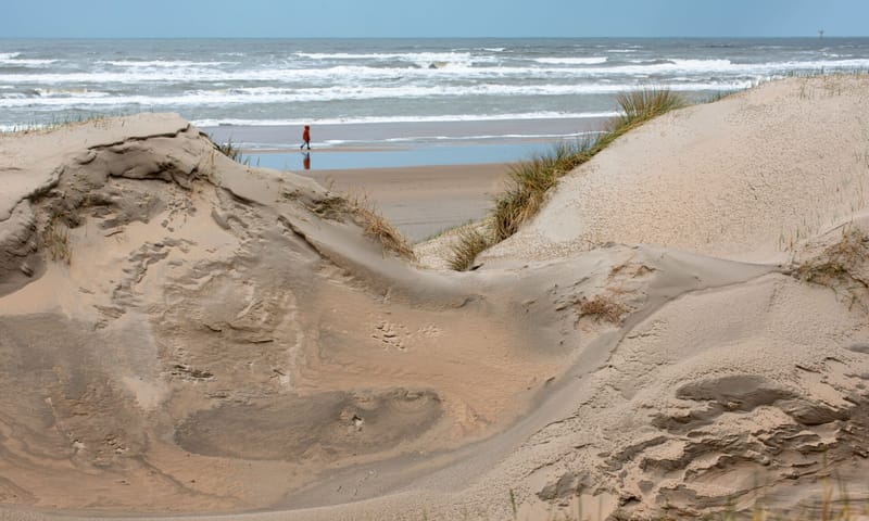 Tussen de duinen door zie je de zee