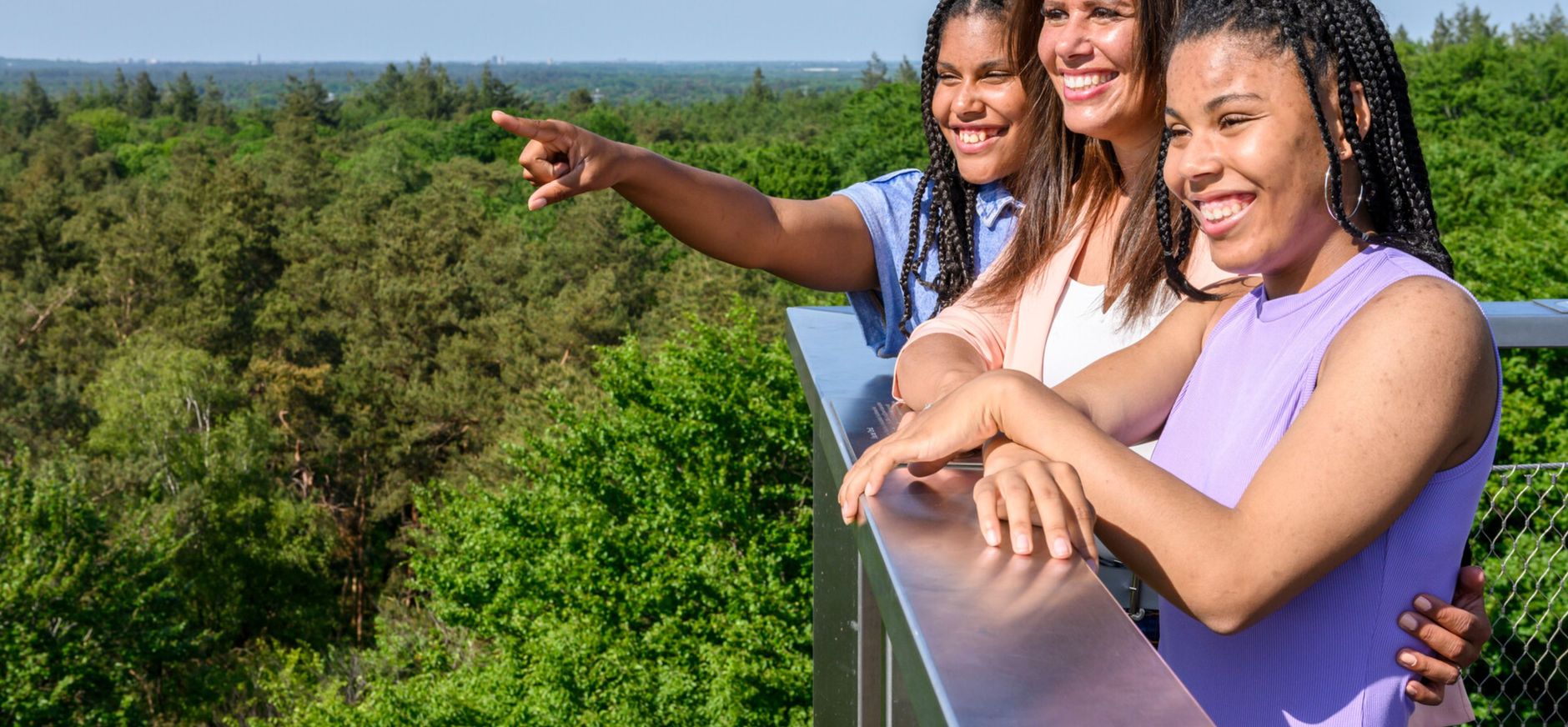 Drie dames die vanaf een uitkijktoren uitkijken over het bos