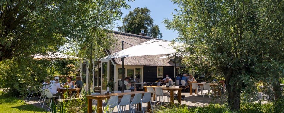 Restaurant in het groen met een terras tussen het gras en bomen