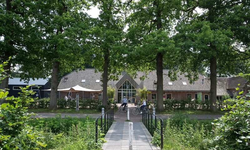 Bruggetje naar een gebouw met daarvoor nog wat bomen