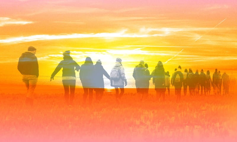 een groep mensen wandelt richting de opkomende zon